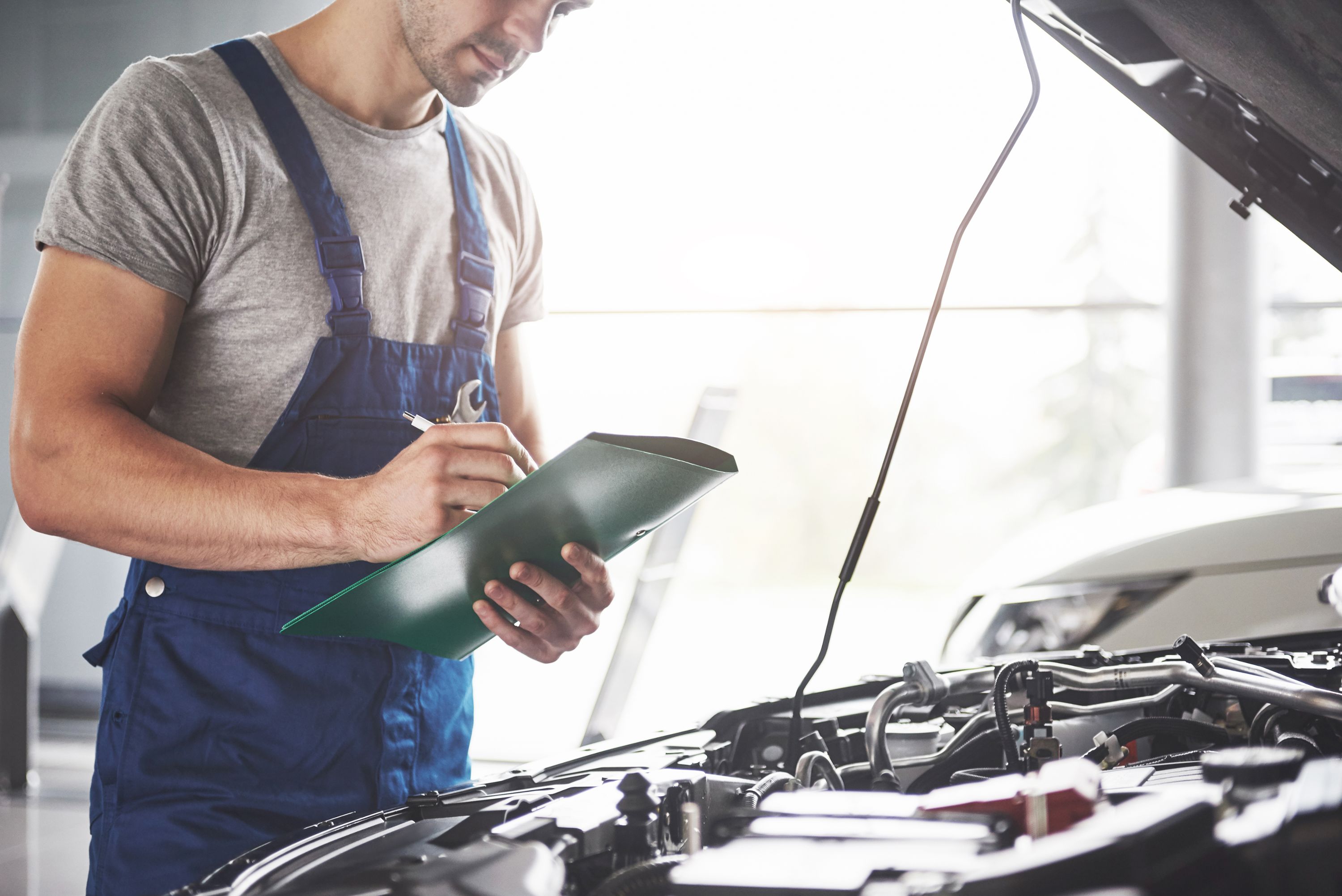 Man looking at car with a check list